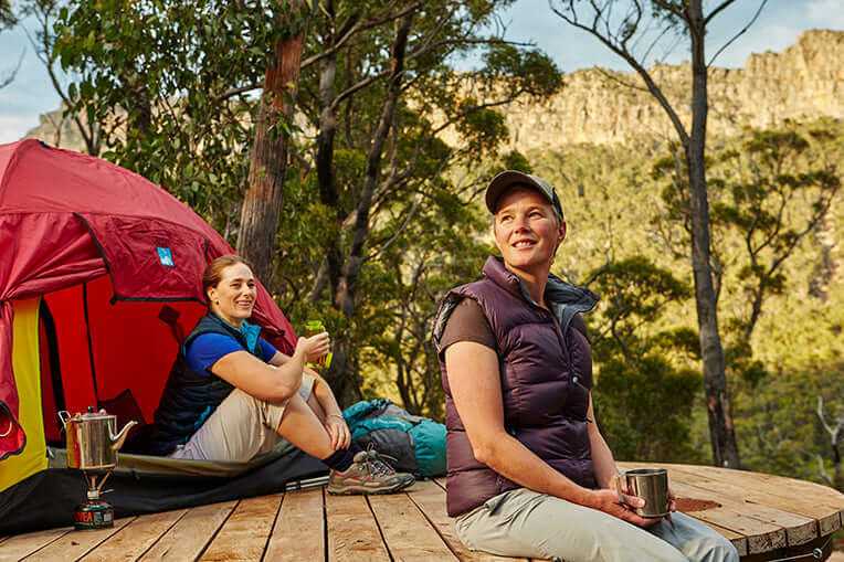Two women enjoying a peaceful moment by a tent in the Grampians, embracing adventure in the outdoors.