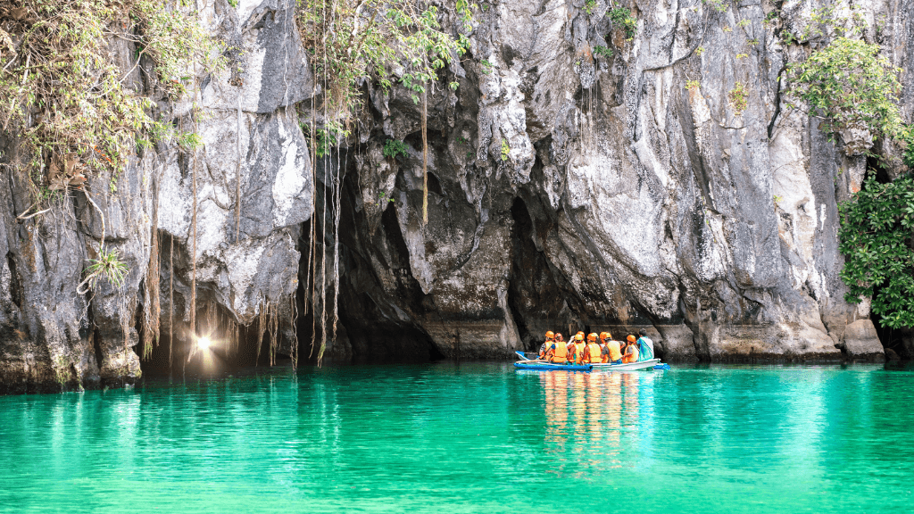 Tourists on a boat entering Puerto Princesa Underground River, part of Philippines Travel Tours - Icons of the Philippines adventure.