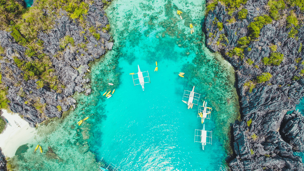 Aerial view of El Nido’s turquoise lagoon with boats, part of Philippines Travel Tours - Icons of the Philippines | 10/14/23 Days.