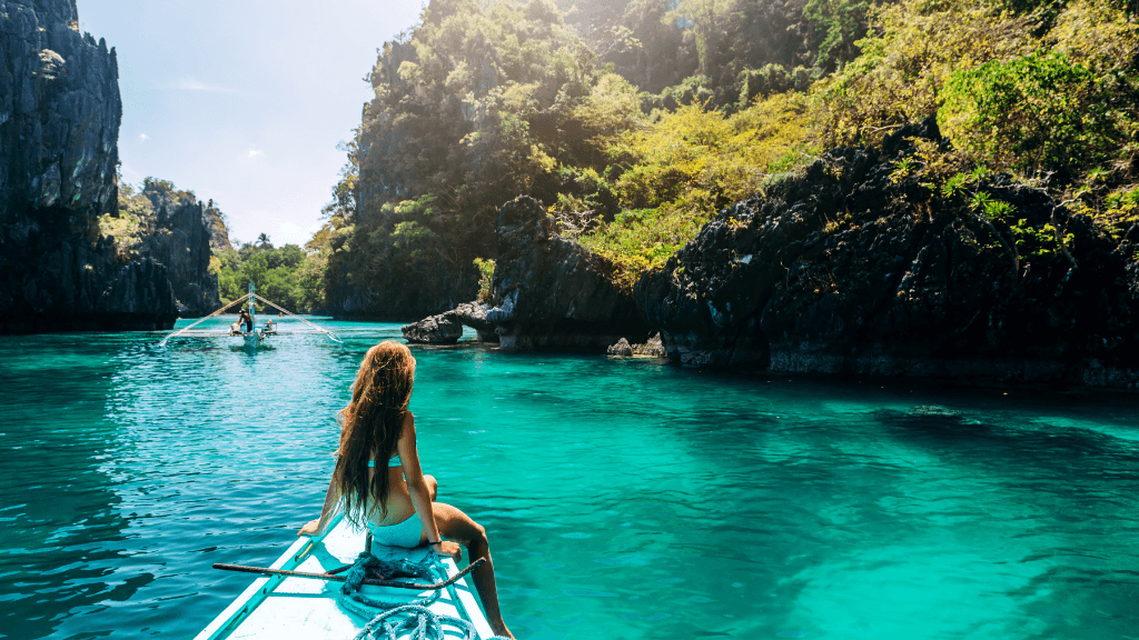 Woman kayaking through turquoise waters in Palawan, part of Philippines Travel Tours - Icons of the Philippines | 10/14/23 Days adventure.