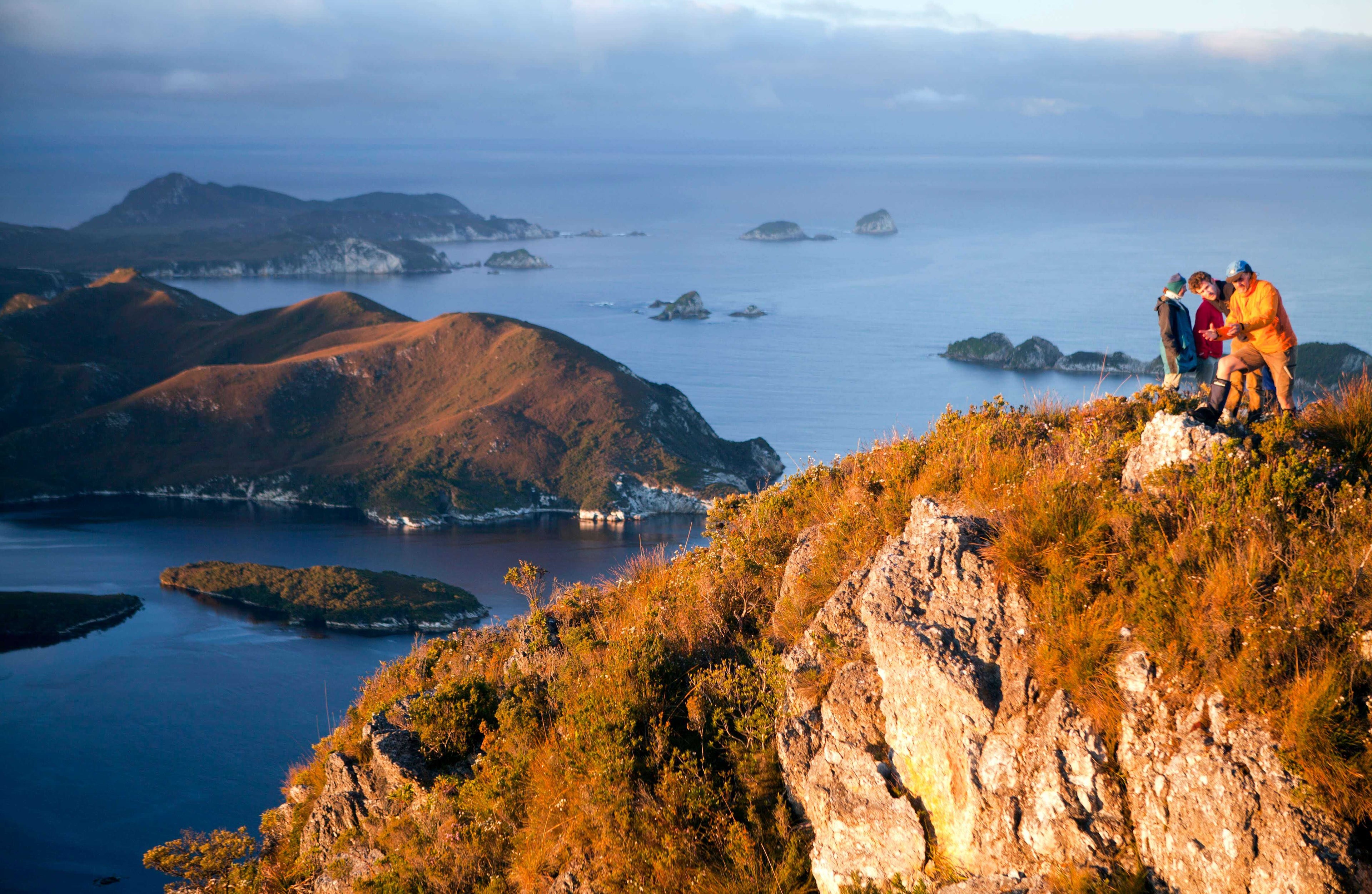 Hikers overlook Tasmania’s rugged coastline and islands during a scenic stop on the 8-day sea kayak and wilderness adventure expedition.