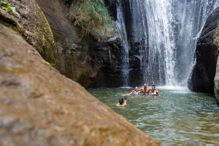 Group swimming under waterfall in Sri Lanka jungle. Explore Sri Lanka - Land & Sea Tour Options includes refreshing natural experiences.