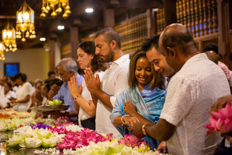 Group participating in flower offering ceremony at temple. Explore Sri Lanka - Land & Sea Tour Options includes immersive religious experiences.