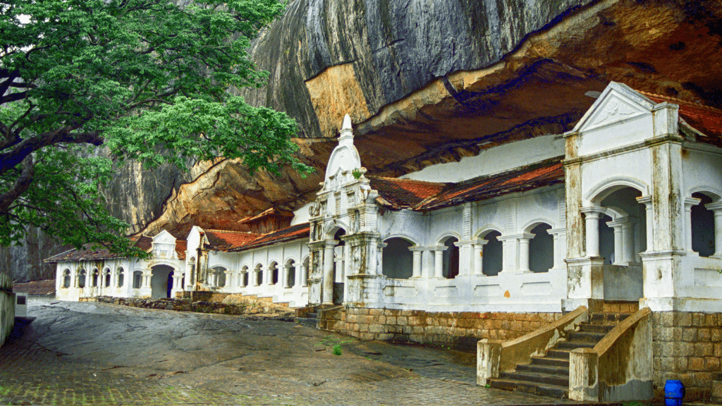 Historic white cave temple built into rock face, featured on the 12-day Sri Lanka tour of spice gardens and cultural sites.