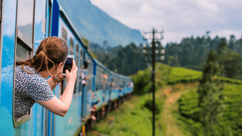 Woman photographing scenic train ride through Sri Lanka's emerald hills on the 12-day tour of spice gardens and tropical coasts.