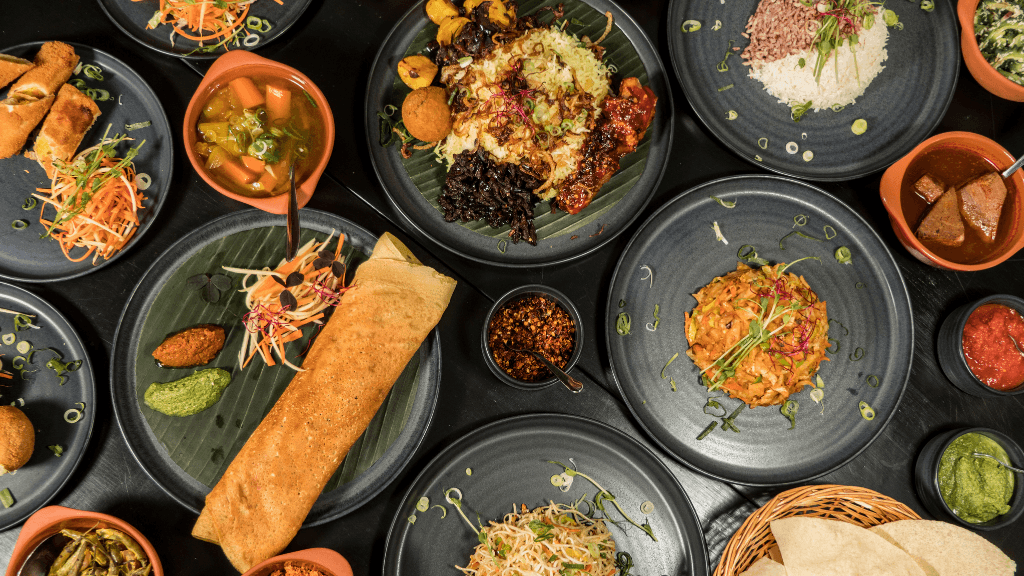 Traditional Sri Lankan dishes served on black plates, showcasing local cuisine on the 12-day spice gardens and coast tour.