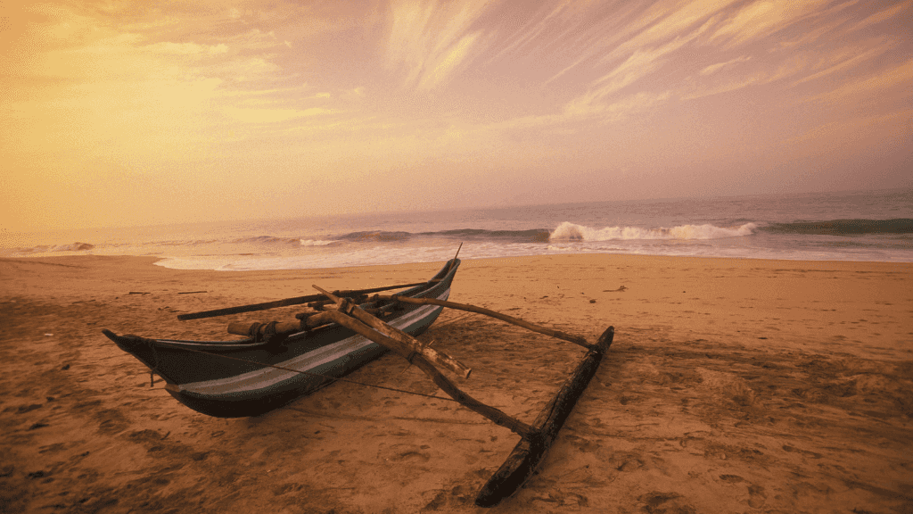 Traditional fishing boat on a golden beach at sunset, showcasing Sri Lanka's coastal charm on the 12-day travel itinerary.