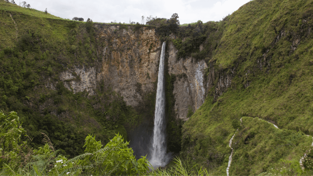 Tall Sipiso-piso waterfall cascading down cliffside, a scenic stop on the Wild Orangutan 8-Day Loop in Sumatra.