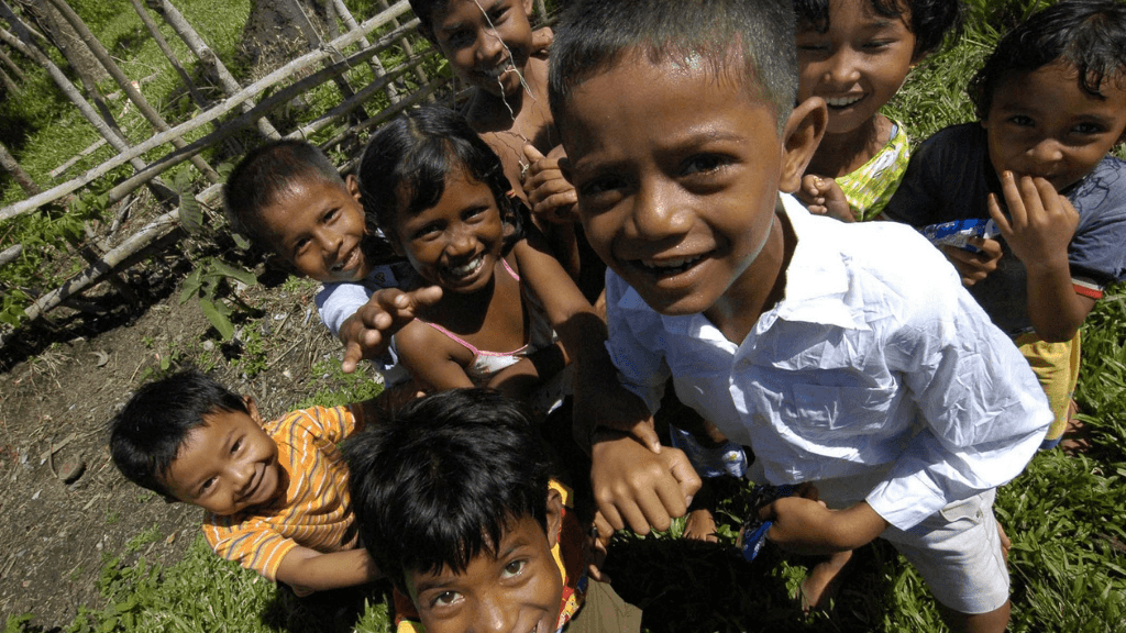 Local children in Kampung Lama village smiling during cultural visit on the Sumatran Jungle River Expedition tour package.