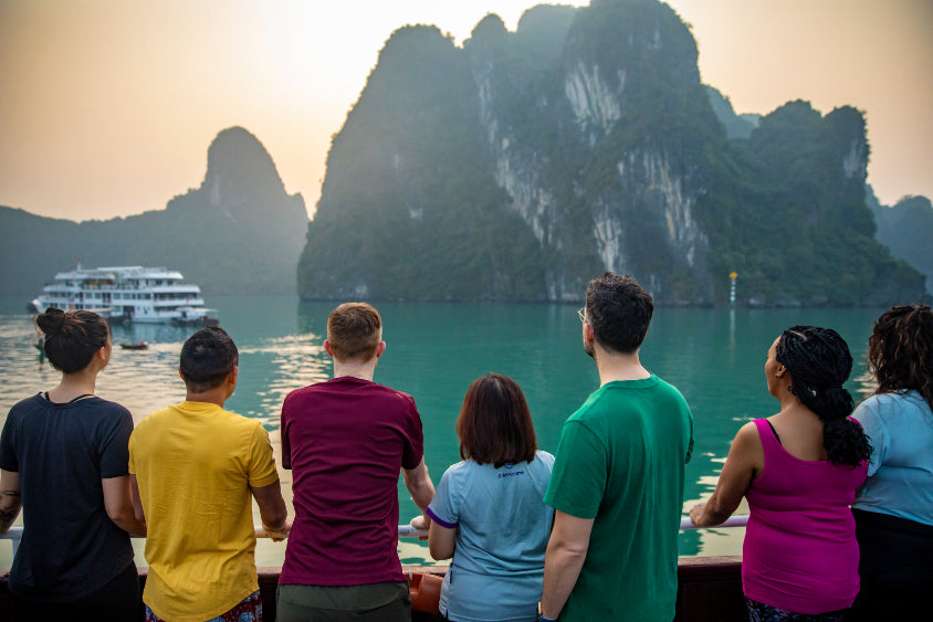 Travelers admiring limestone karsts from a cruise deck in Hạ Long Bay. Scenic highlight of Vietnam Hiking and Cycling Tour.