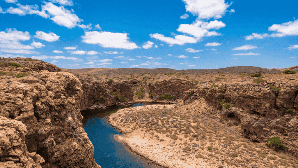 Rocky gorge and river bend under blue sky in Cape Range, a scenic stop on the Ningaloo Kayak Expedition - 4-Day Trek & Camp Adventure.