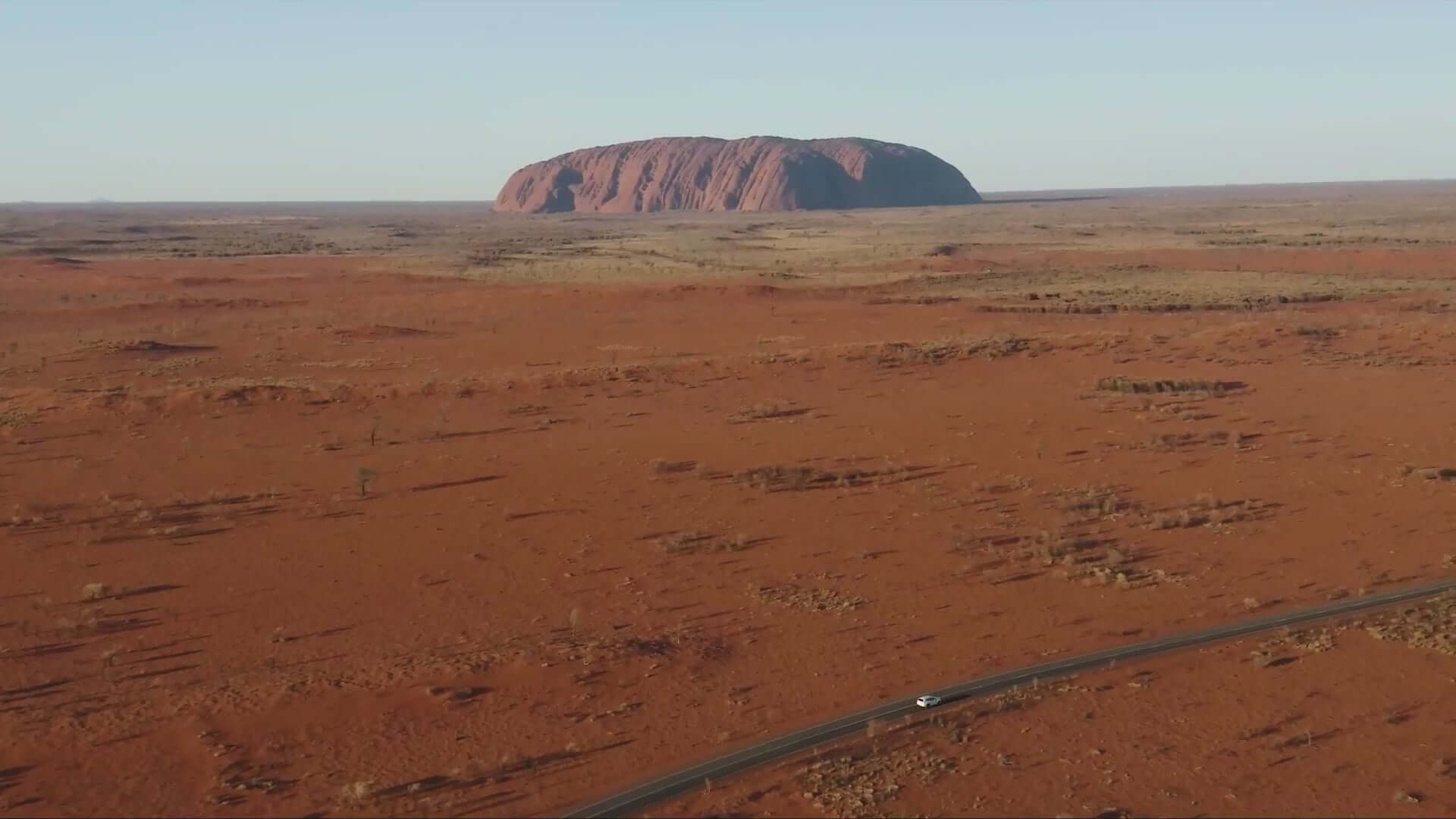 Aerial view of Uluru rising from the vast desert landscape, a highlight of the Uluru & Kings Canyon 4WD Safari adventure.