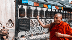 Elderly monk spinning prayer wheels along the Trans Bhutan Trail, showcasing spiritual moments on this cultural adventure.
