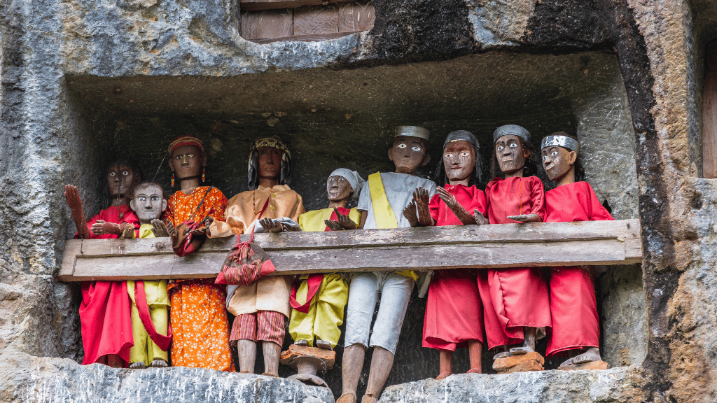 Tau-tau wooden effigies in cliffside graves of Tana Toraja, a sacred tradition on the Soul of Sulawesi - Tana Toraja Culture Tour.