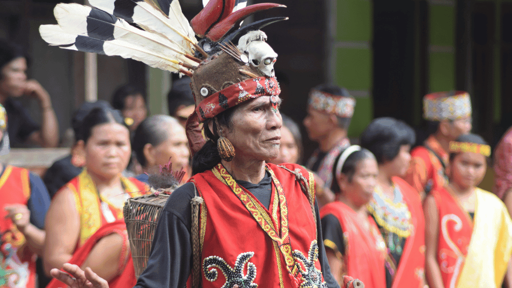 Dayak tribesman in traditional attire during cultural event, part of Borneo orangutan and heritage tour experience.
