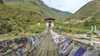 Suspension bridge covered in prayer flags along the Trans Bhutan Trail, a scenic stop on the Camping or Hotel Adventures tour.