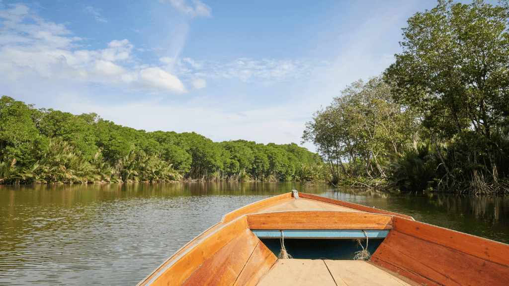 View from wooden boat cruising Borneo river, part of 7-day klotok river and orangutan adventure tour in lush rainforest.