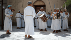 Omani men in traditional dress performing music and dance, a cultural experience on the Oman 8 Day Adventure - Desert Stars & Turtle Shores tour.