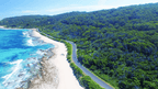 Aerial view of coastline road near turquoise waters and lush greenery, perfect for outdoor adventure tours.