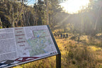 Trail sign for Australian Alps Walking Track with hikers in background on Mt Bimberi & Blue Waterholes tour.