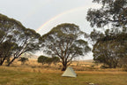 Tent pitched under rainbow in open field during Mt Bimberi & Blue Waterholes camping experience in Australia.