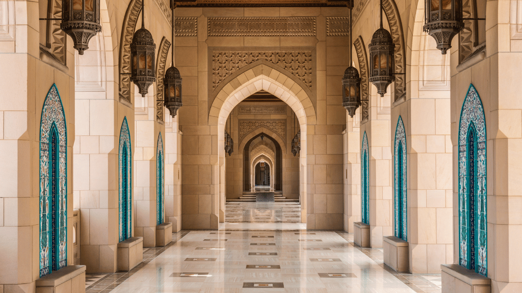 Intricate Islamic arches and lanterns in Sultan Qaboos Grand Mosque, a highlight of the Oman 8 Day Adventure - Desert Stars & Turtle Shores tour.