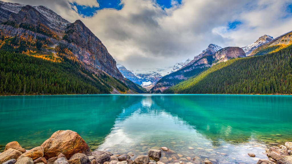 Lake Louise with turquoise water, rocky shore, and snow-capped mountains.