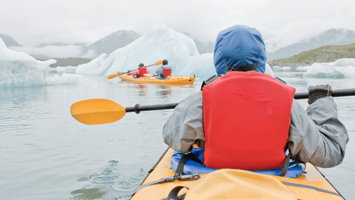 Kayakers paddling near icebergs in Kenai Fjords, a key activity on the 8-Day Alaskan Adventure: Glaciers & Grizzlies tour.