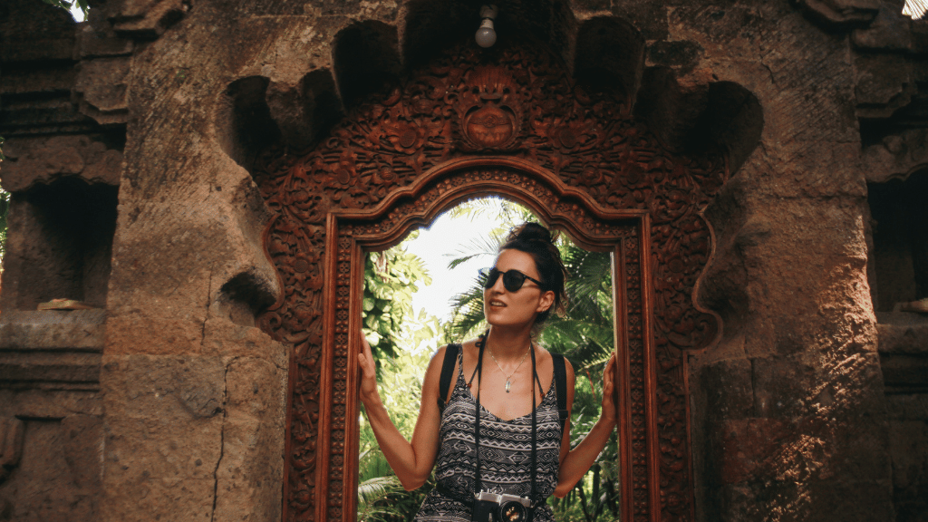 Female tourist posing in carved temple doorway, enjoying cultural exploration on the Soul of Sulawesi - Tana Toraja Culture Tour.