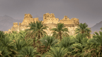 Ancient ruins atop a hill surrounded by palm trees, showcasing Oman's history on the Oman 8 Day Adventure - Desert Stars & Turtle Shores experience.