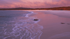 Beach at sunset with pink and purple sky