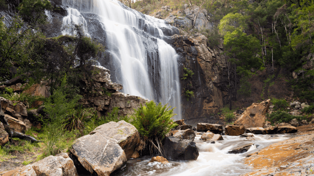 Majestic waterfall cascading down rocky cliffs in lush greenery, perfect for adventure seekers and nature lovers.