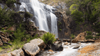 Majestic waterfall cascading down rocky cliffs in lush greenery, perfect for adventure seekers and nature lovers.