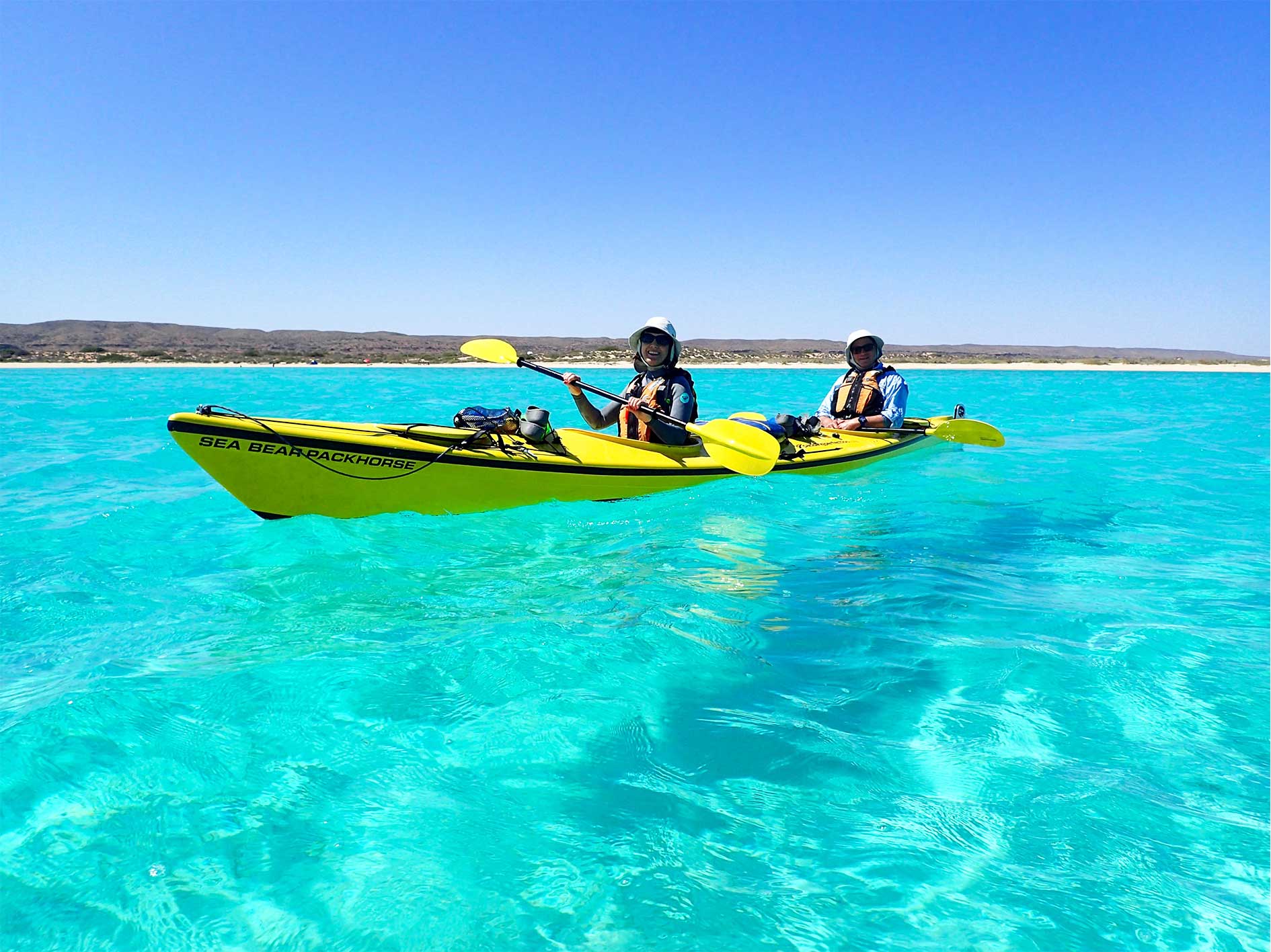 Two kayakers paddling in clear turquoise waters on the Ningaloo Safari 3-Day Tour. Ideal for ocean kayaking adventures in Australia.