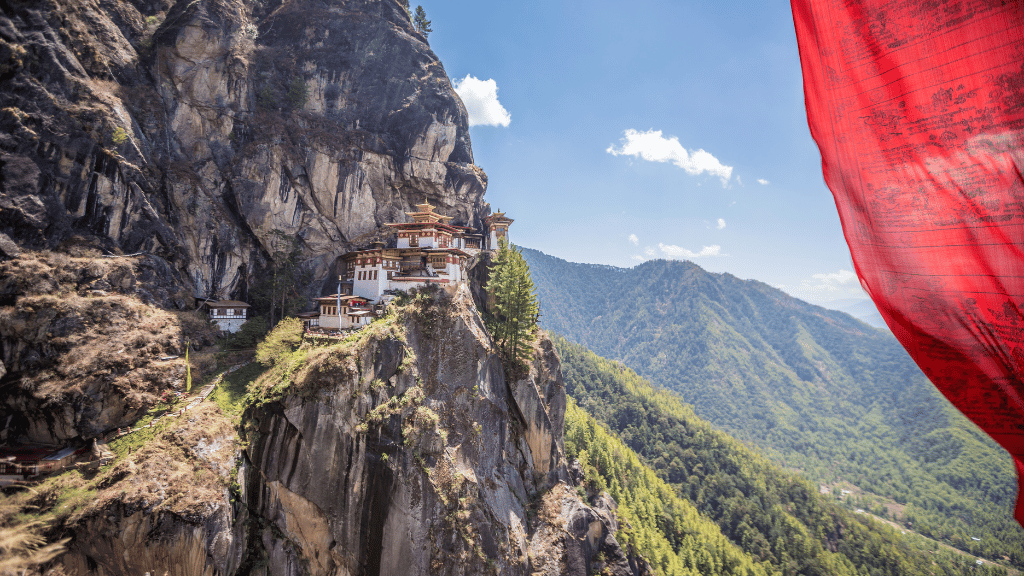 Tiger’s Nest Monastery with red prayer flag in foreground, a dramatic view on the Trans Bhutan Trail tour.