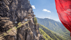 Tiger’s Nest Monastery with red prayer flag in foreground, a dramatic view on the Trans Bhutan Trail tour.