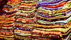 Stacks of colorful silk scarves in a Central Asian market, showcasing local crafts on the 14-23 Day Central Asia Silk Road Tour.