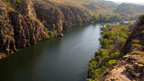 Scenic view of Nitmiluk Gorge showcasing a tranquil river and lush greenery, perfect for outdoor adventure tours.
