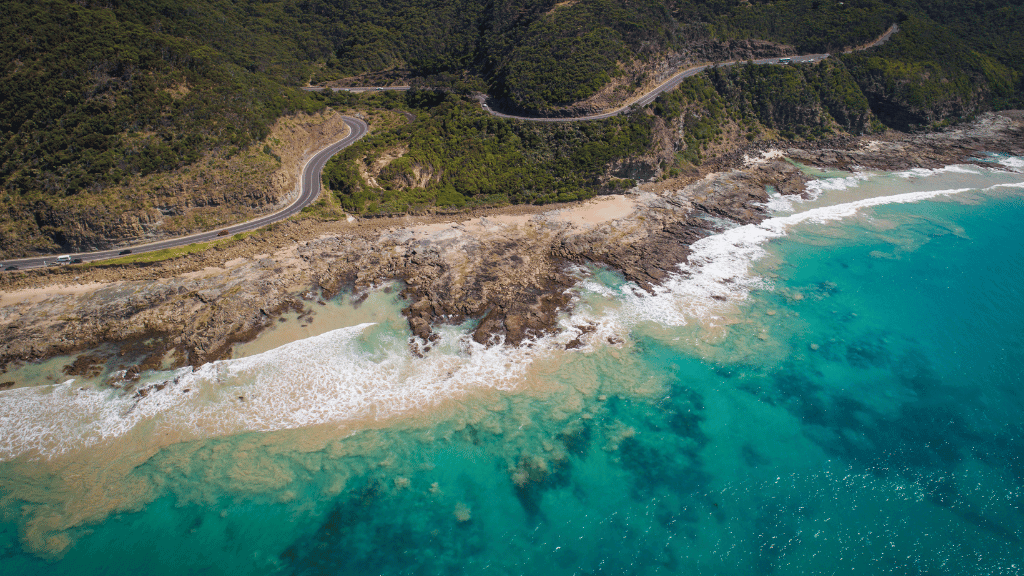 Aerial view of Victoria's Southern coastline featuring turquoise waters and winding roads along rugged cliffs.