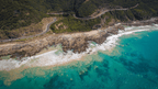 Aerial view of Victoria's Southern coastline featuring turquoise waters and winding roads along rugged cliffs.