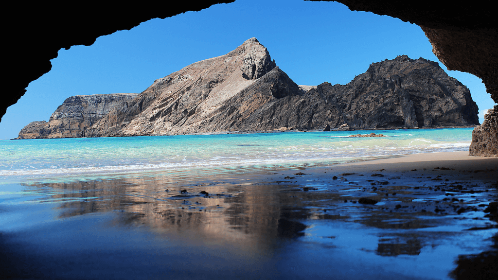 Secluded beach and rocky cliffs viewed from a cave in Madeira, a hidden gem on the 6-days hiking Madeira’s trails.