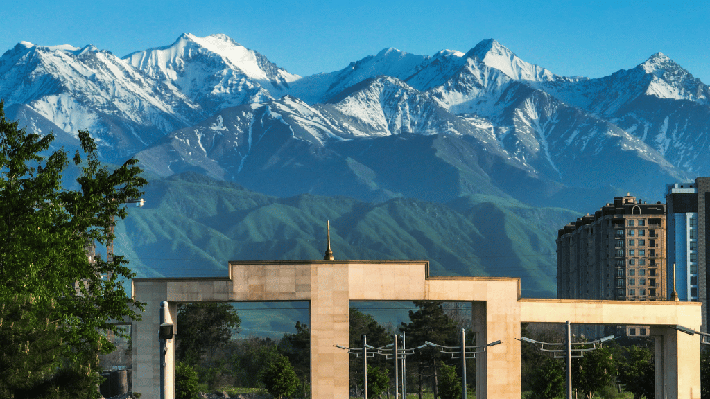 Snow-capped mountains rising behind Almaty’s cityscape, a striking contrast seen on the 14-23 Day Central Asia Silk Road Tour.