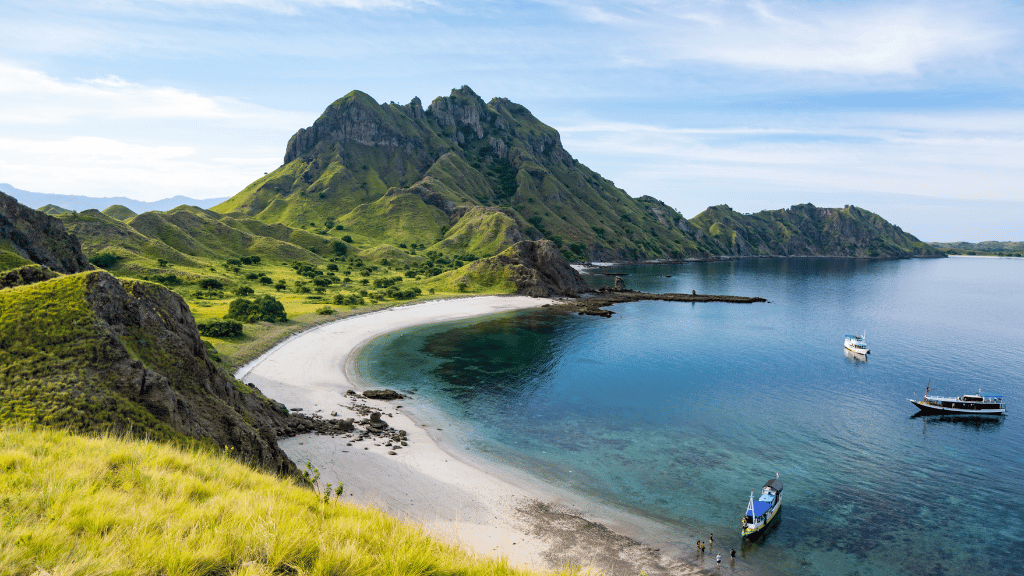Padar Island with boats anchored in turquoise water, a key destination in Bali Komodo Lombok Tours - Explore Culture & Nature.