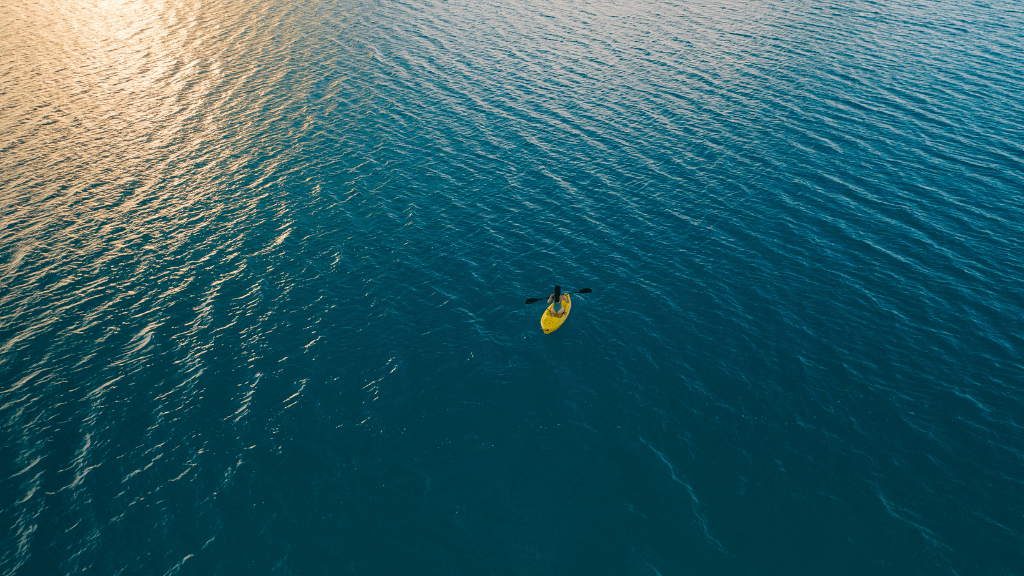 Solo kayaker paddling at sunset on calm ocean waters during the Ningaloo Safari 3-Day Tour. Ideal for tranquil outdoor escapes.