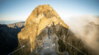 Hiker crossing a narrow mountain ridge trail in Madeira, a thrilling part of the 6-days hiking Madeira’s trails adventure.
