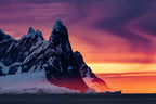Snowy mountain peak with a vibrant sunset sky transitioning from purple to orange.