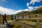 Group of hikers on a trail with mountains and blue sky in the background