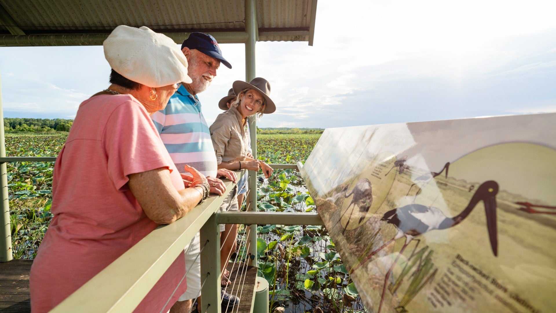Group reads birdwatching sign on wetland boardwalk on Kakadu Katherine Gorge Tour | 4-Day Comfort Travel. Educational eco-tour experience.
