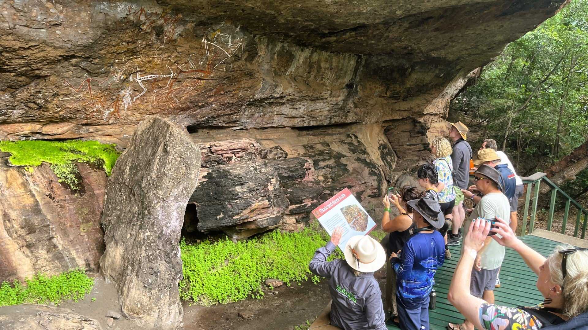 Tour group photographs Aboriginal rock art under cliff on Kakadu Katherine Gorge Tour | 4-Day Comfort Travel. Cultural heritage exploration.