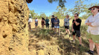 Tour group listens to guide near termite mound on Kakadu Katherine Gorge Tour | 4-Day Comfort Travel. Nature education in outback setting.